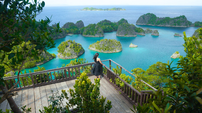 Femme regardant les îles sur une terrasse surélevée dans un décors de l'Indonésie